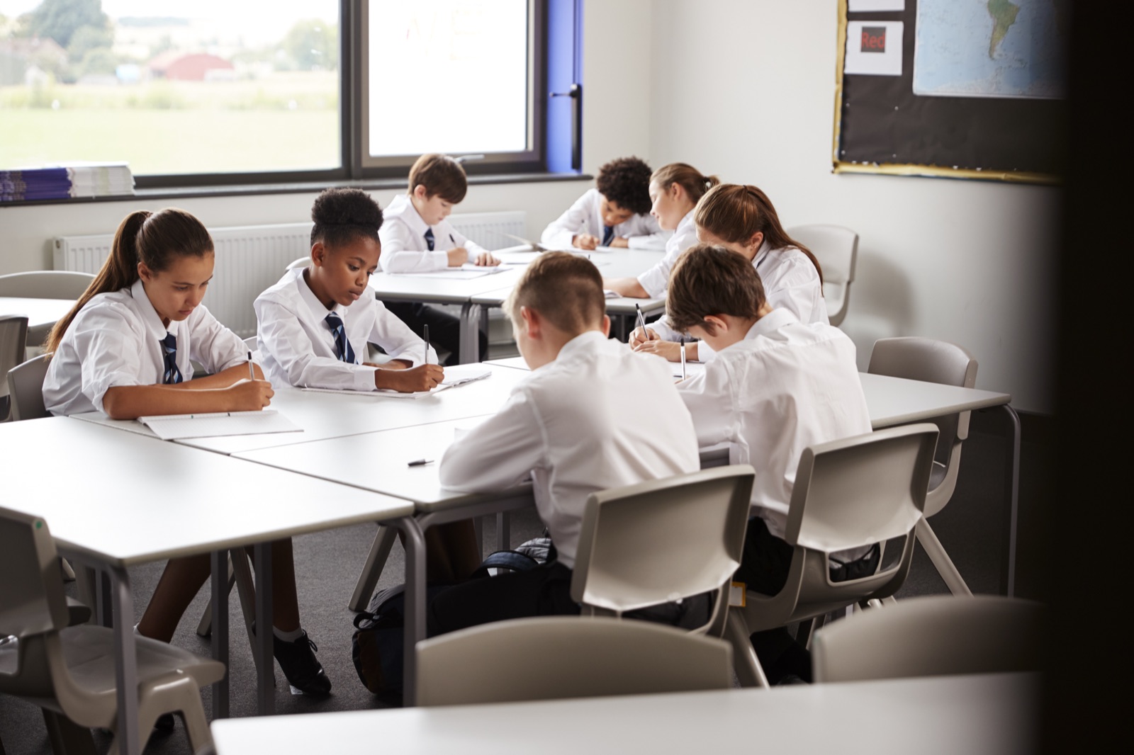 Students in uniform writing at their desks
